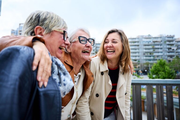 Three women with the around each other laughing.