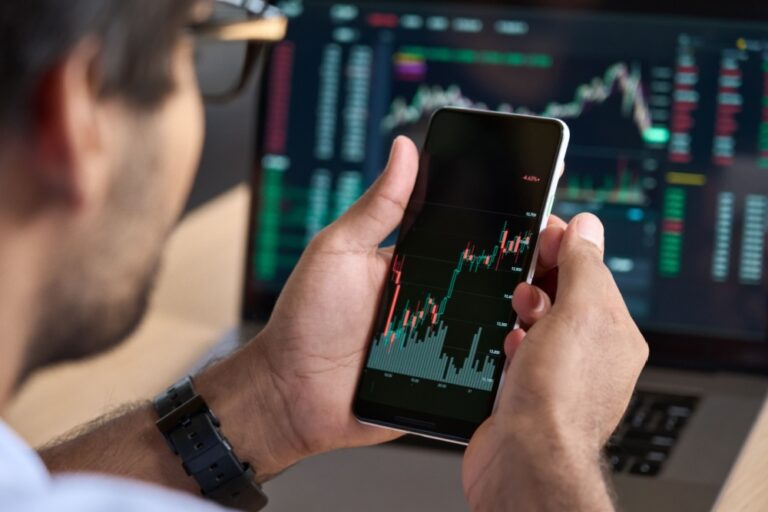 A man looking at a graph showing stock market performance on his phone.