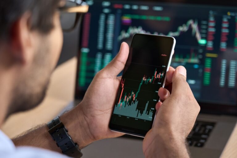 A man looking at a graph showing stock market performance on his phone.