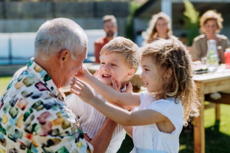 A grandfather playing with his grandchildren outdoors.