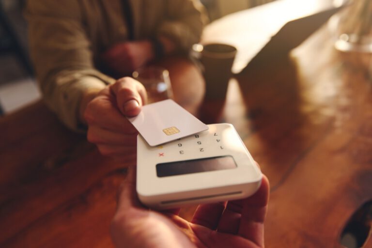 A person using their debit card to pay in a café.