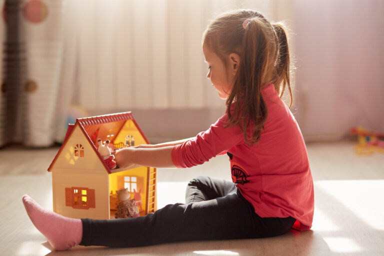 A girl playing with a dollhouse.