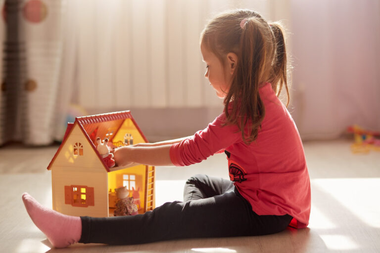 A girl playing with a dollhouse.