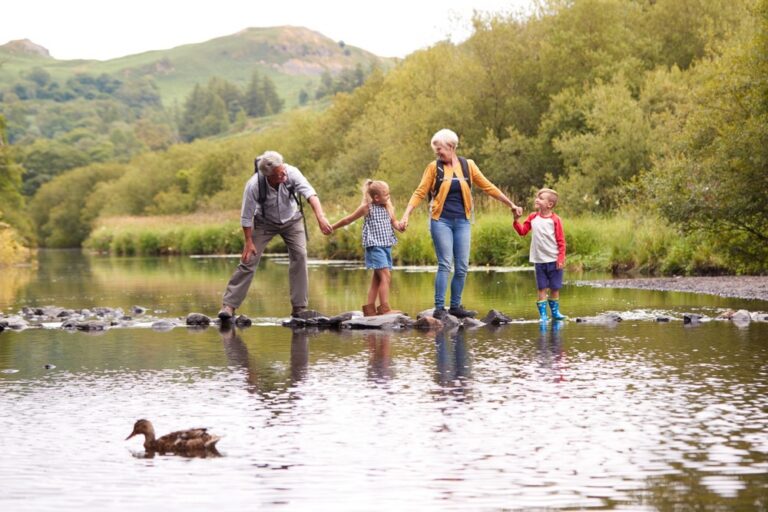 A family walking across stepping stones in a park.