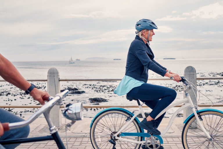 A woman cycling along a beachfront.