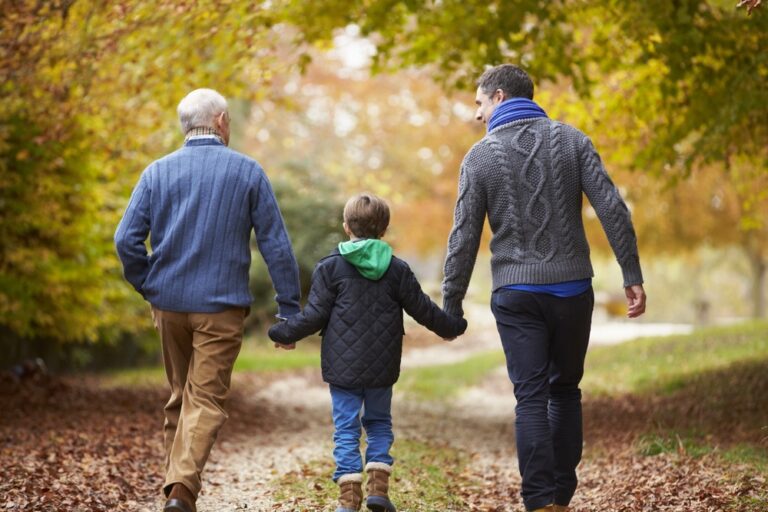 A grandfather walking with his son and grandchild.