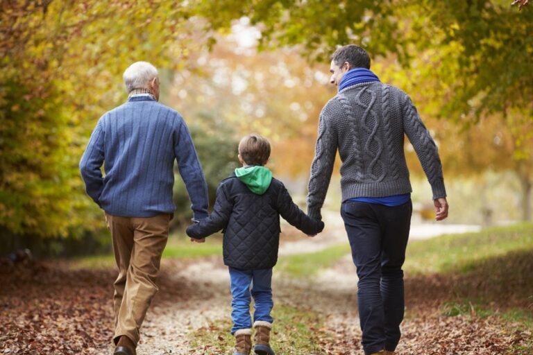 A grandfather walking with his son and grandchild.
