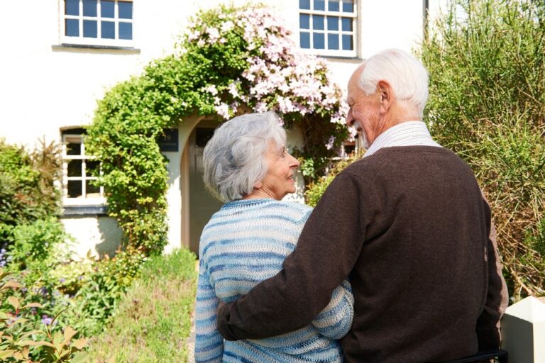 Rear view of senior couple outside pretty cottage